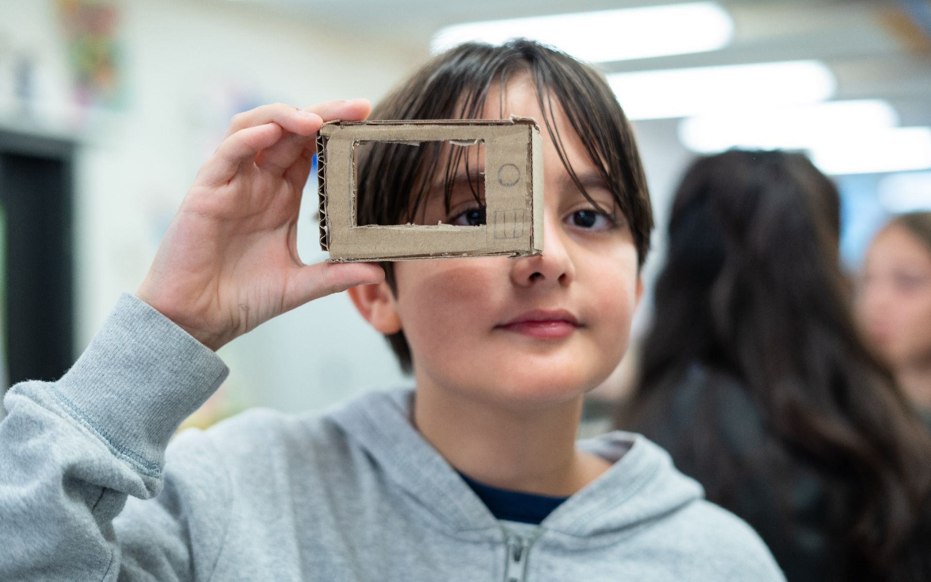photo of ISSH student holding up a piece of card and looking through it