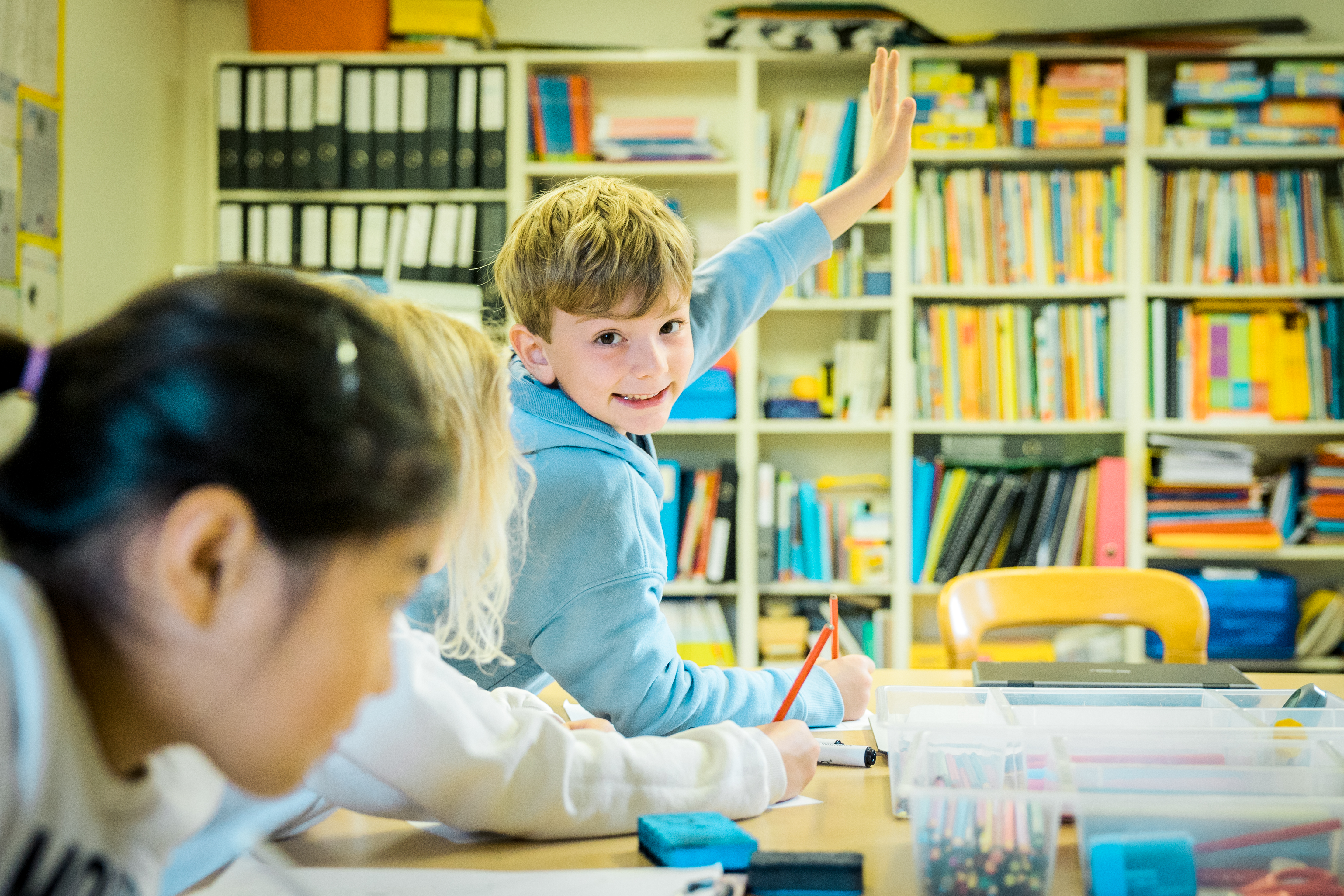 photo of boy raising his hand and smiling